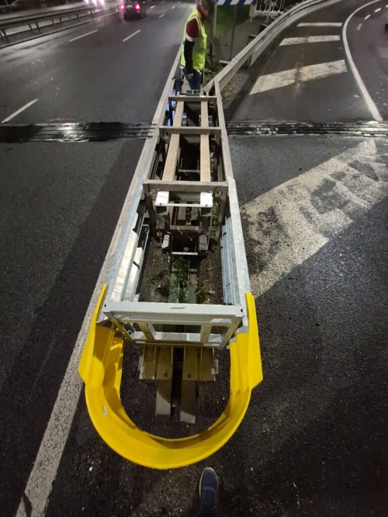 Operario instalando barrera metálica en carretera nocturna
