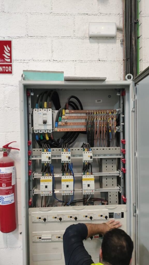 Técnico revisando cuadro eléctrico en sala de control.