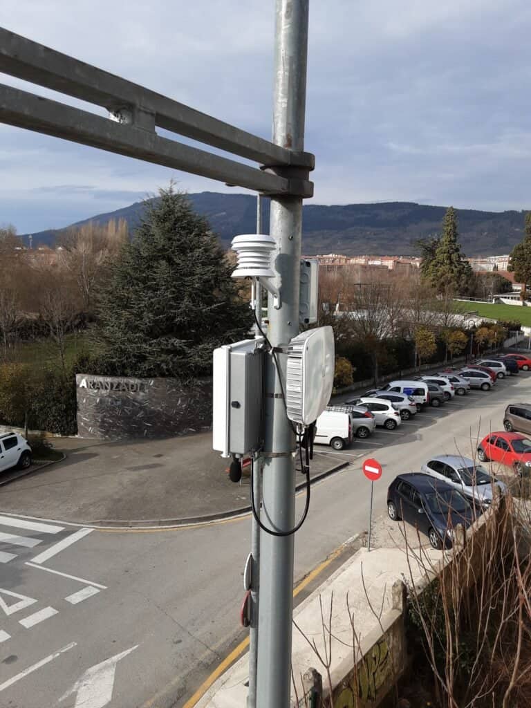 Sensor en poste junto a aparcamiento y paisaje montañoso.
